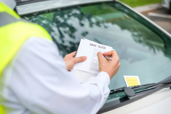 One parking warden writing a ticket for a parking violation