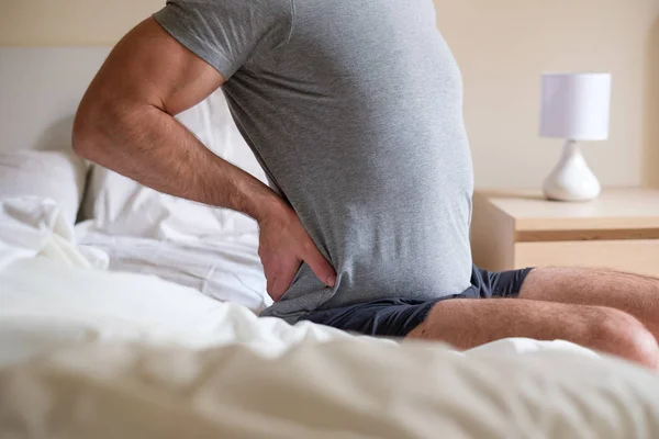 Hombre sintiendo dolor de espalda después de dormir en la cama —  Fotos de Stock