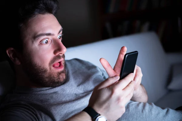 Expresión del hombre sorprendido usando el teléfono por la noche — Foto de Stock