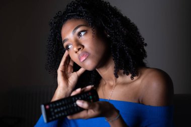 One black woman watching television at night clipart