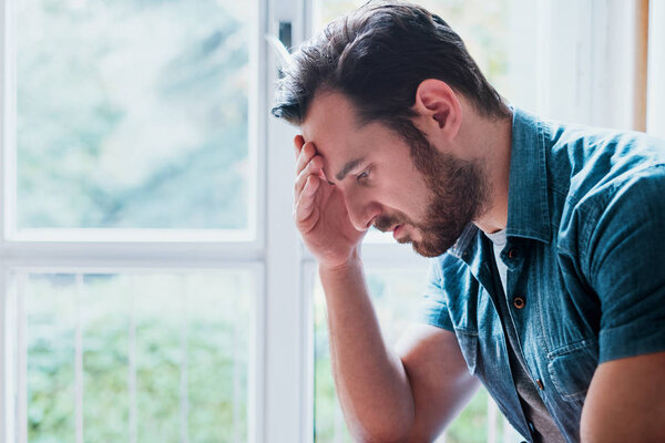 Worried man looking thoughtful out of window