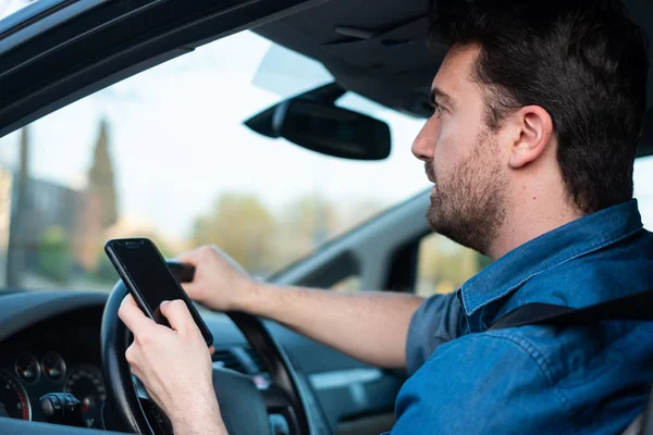 Мужчина за рулём машины и смс-ки по мобильному — стоковое фото