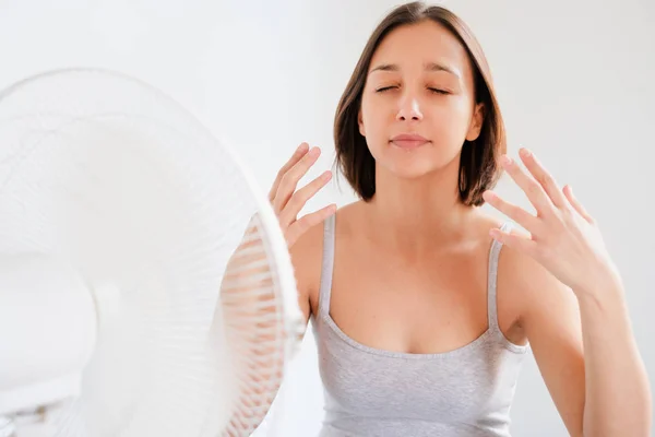 Mulher refrescante na frente de um ventilador elétrico — Fotografia de Stock