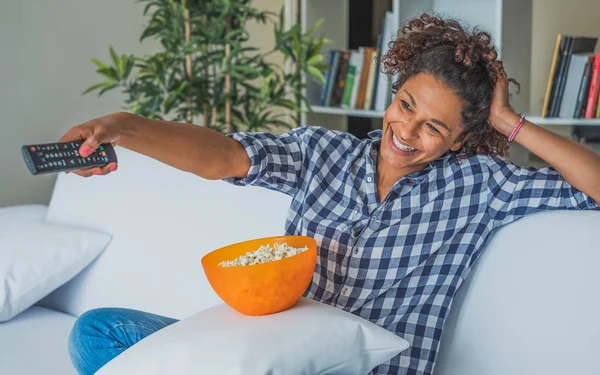 Afro vrouw om thuis te zitten met afstandsbediening tv kijken — Stockfoto