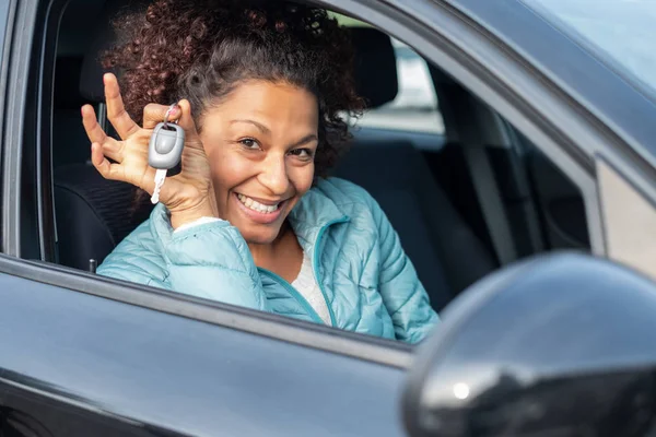 Mulher negra segurando chaves para carro novo e sorrindo para a câmera — Fotografia de Stock