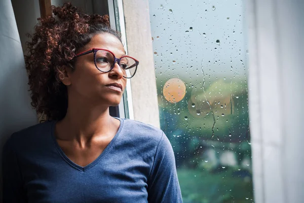 Einsame schwarze Frau am Fenster denkt über etwas nach — Stockfoto