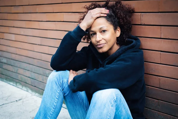 Portrét afro americký žena sedí u stěny — Stock fotografie