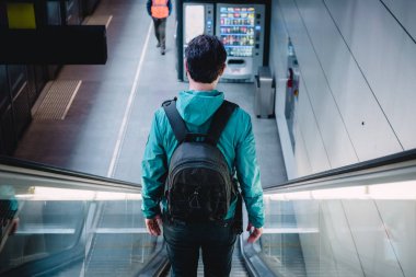 Metro yürüyen merdiveninde genç bir gezgin.