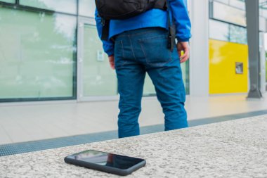 Kişi sokakta bir bankta akıllı telefon unutur