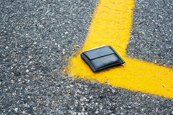 Schwarze Geldbörse mit Bargeld liegt verloren auf dem Gehweg — Stockfoto