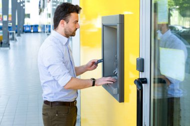 Adam nakit para çekmek için bir atm bir kredi kartı kullanarak