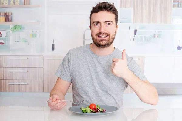 Молодой человек, сидящий на диете и питающийся свежим салатом — стоковое фото