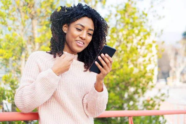 Black woman holding mobile phone outdoor