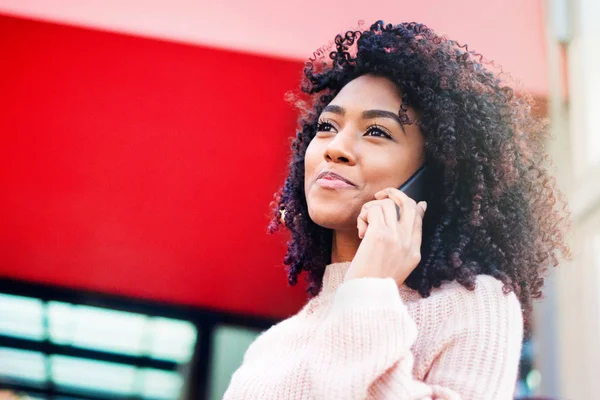 Black woman holding mobile phone outdoor