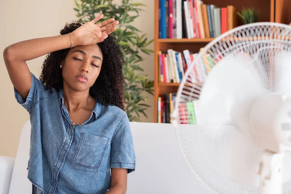 Svart kvinna uppfriskande framför en fläkt under sommarvärmen — Stockfoto