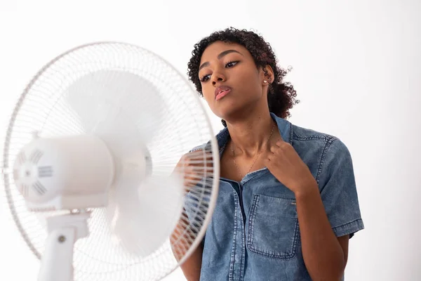 Svart kvinna uppfriskande framför en fläkt under sommarvärmen — Stockfoto