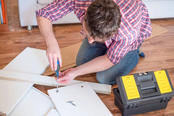 Homem montando móveis em casa no chão — Fotografia de Stock