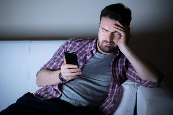Homem sentindo-se deprimido usando telefone à noite — Fotografia de Stock