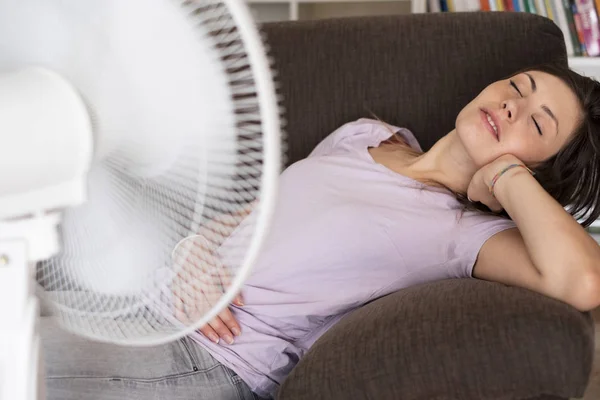 Jovem relaxante sob o ventilador de ar em casa — Fotografia de Stock