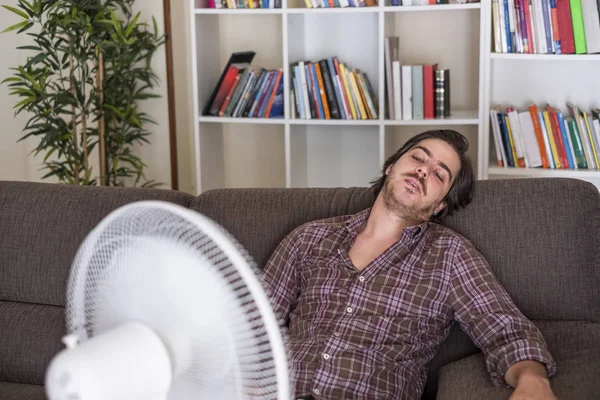 Homem refrescante com ventilador elétrico contra onda de calor de verão — Fotografia de Stock