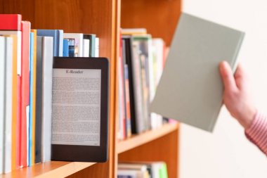 Öğrencinin okul Kütüphanesi içinde bookshelf içinde dijital tablet tutmak el