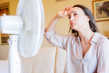 Yenilenmeye çalışan elektrikli fan önünde Kız