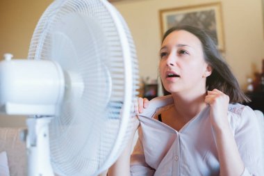 Yenilenmeye çalışan elektrikli fan önünde Kız
