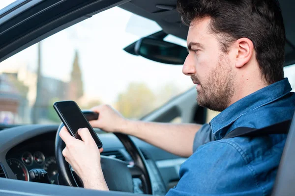 Mężczyzna w samochodzie przy użyciu telefonu komórkowego za kierownicą — Zdjęcie stockowe