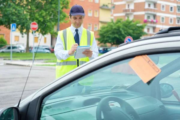 Un guardia de estacionamiento escribiendo una multa por una violación de estacionamiento — Foto de Stock