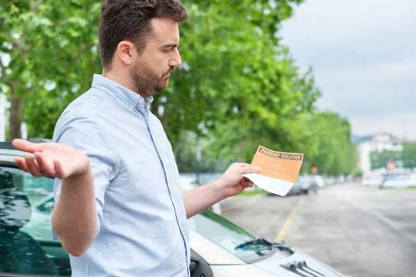 Hombre sorprendido encontrar multa multa multa multa de estacionamiento en su coche — Foto de Stock