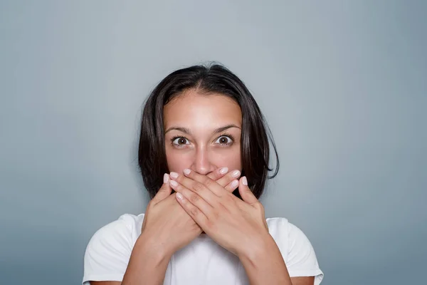 Jeune femme faisant un geste de silence sur fond gris — Photo