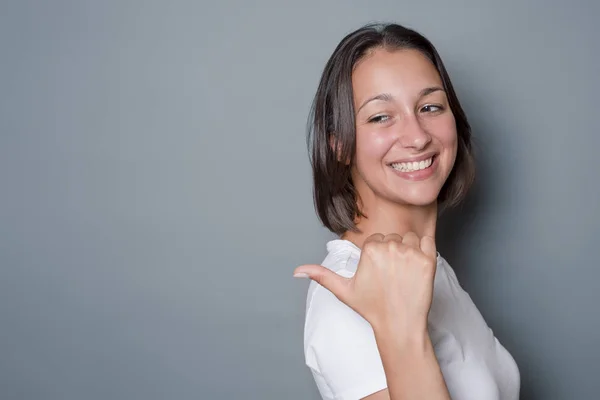 Mujer mostrando un mensaje sobre fondo gris — Foto de Stock