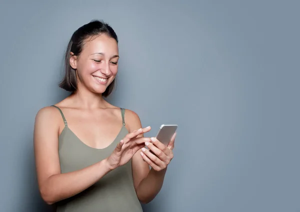 Retrato de menina usando telefone celular no fundo cinza — Fotografia de Stock