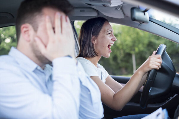 Instructor of driving school giving exam while sitting in car