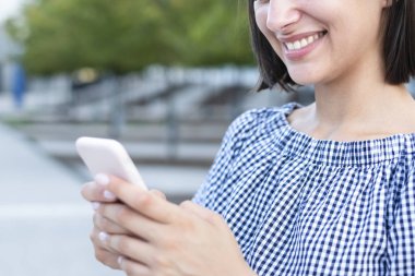 Şehirde cep telefonuyla mesajlaşan genç bir kız.