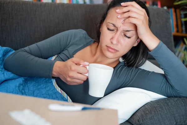 Femme malade couverte d'une couverture sur le canapé avec une forte fièvre et — Photo