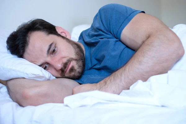 Uomo che si sente male e triste di notte sdraiato nel suo letto — Foto Stock