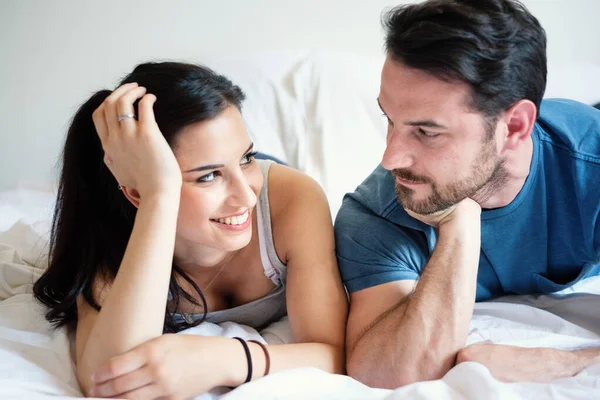 Amor casal deitado na cama beijando e olhando uns aos outros — Fotografia de Stock