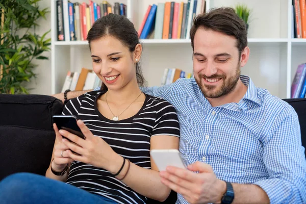 Jeune couple relaxant et utilisant un smartphone à la maison — Photo