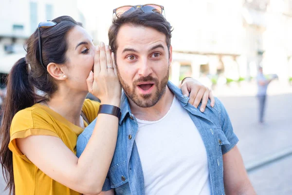 Mulher está sussurrando um segredo em seu ouvido namorados — Fotografia de Stock