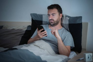 Bir adam gece geç saatlerde cep telefonundan mesaj atıyor.