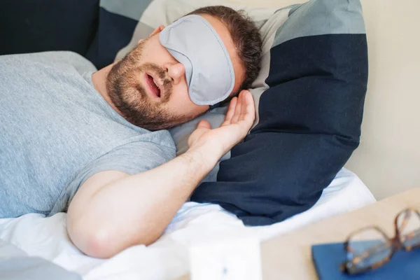 男の肖像画でベッドの中に眠っている目のマスク感快適な — ストック写真