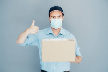 Teslimatçı arka planda yüz maskesi takıyor.