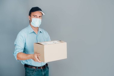 Teslimatçı portresi gri arka planda, maske takıyor.