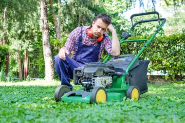 One guy portrait cutting the garden grass having problem with the lawn mower clipart