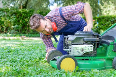 One guy portrait cutting the garden grass having problem with the lawn mower clipart