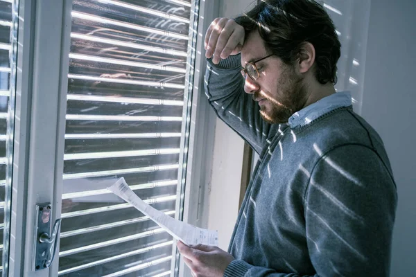 Frustrated disappointed guy reading a financial letter at home