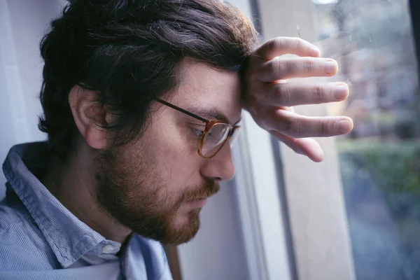 Portrait of one guy longing and looking through window