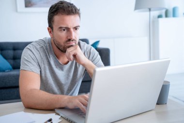 Bilgisayar ve internet bağlantısı kullanarak evden çalışan bir adam