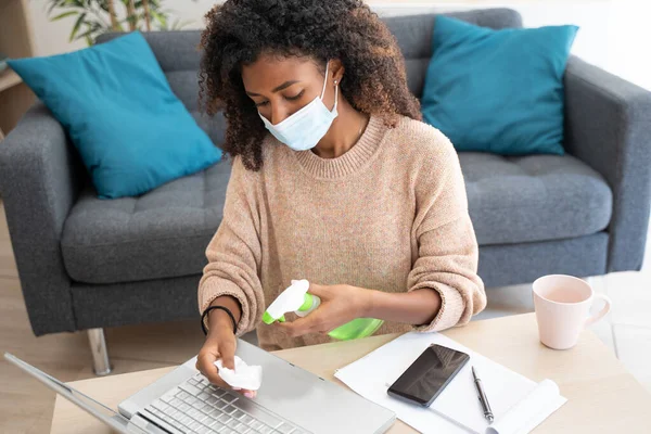Young black woman sanitizing tech stuff during coronavirus pandemic